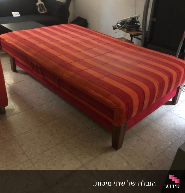 מיטה עם כיסוי פסים אדום כתום על רצפת אריחים
